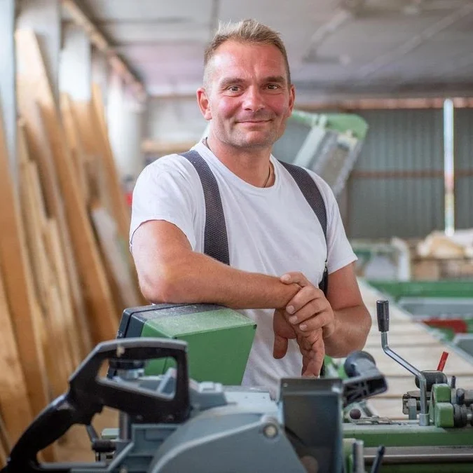 Geschäftsführer Marco Hohbein steht in einer Werkstatt, umgeben von Maschinen und Holz.