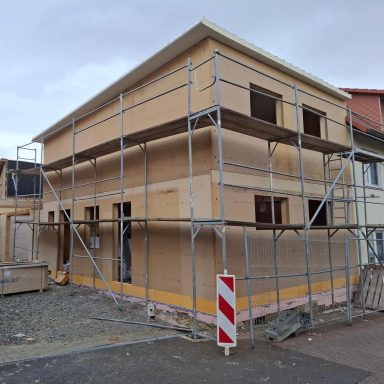 Neues Gebäude im Bau, umgeben von Baugerüst und Baustellenmaterial.